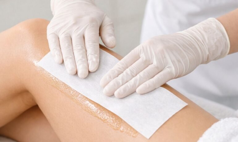 Esteticista aplicando banda depilatoria en pierna de cliente en centro de estética